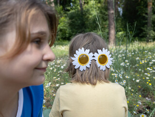 Funny portrait of two children, a girl in profile out of focus and a boy's head in daisy-shaped...