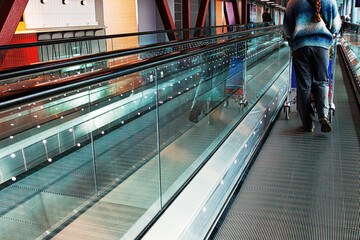 Traveler pushing a luggage trolley on an airport walkway. Passenger walks with travel cart across a...