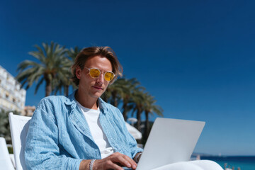 Freelancer working remotely from beach resort using laptop