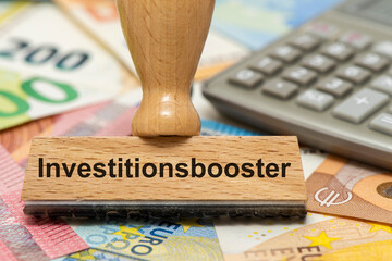 Ein Holzstempel ist beschriftet mit dem Aufdruck Investitionsbooster