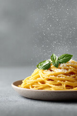 Delicious spaghetti with fresh basil and falling parmesan on a neutral background. Represents comfort food, culinary arts, and healthy eating. Perfect for restaurant menus and food blogs.