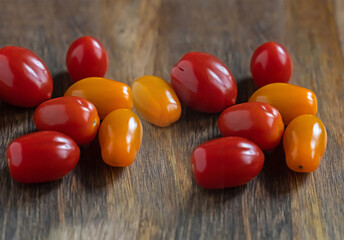 red and yellow cherry tomatoes lies on a dark wooden background
