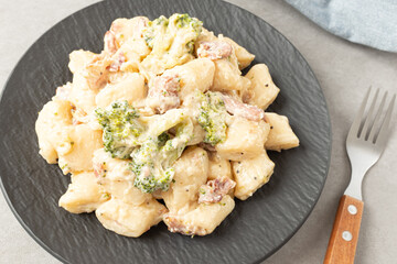 Cream Tteokbokki Korean Rice Cake with Bacon and Broccoli on Black Plate