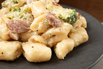 Cream Tteokbokki Korean Rice Cake with Bacon and Broccoli on Black Plate