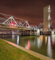 Massive illuminated bridge at night, reflected in the river, Port of Antwerp, Belgium