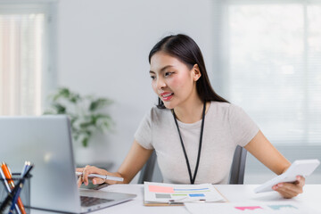 Young Asian businesswoman calculating financial and accounting information using calculator and...