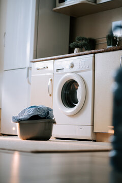 Washing dirty clothes in a modern laundry room with a washing machine and basket on a sunny day