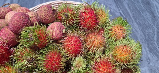 Rambutan and lychees in a basket on a marble table. Juicy fresh fruit.