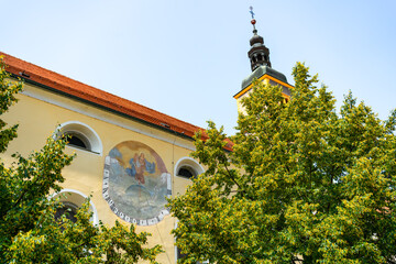 A painted sundial with religious imagery decorates the yellow wall of a Church of St. John the...