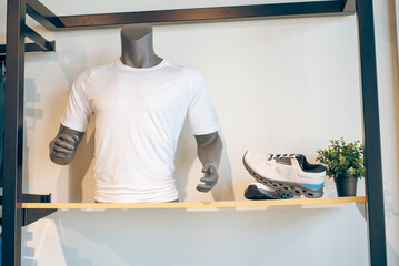 Retail display featuring white performance shirt on mannequin, running shoes, artificial shop tree...