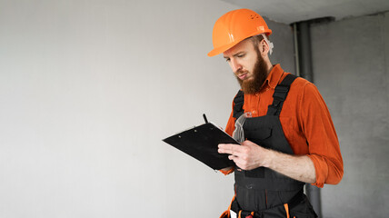 Concept of repair, construction and building. Construction worker with clipboard wearing helmet...