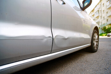 Doors damage, car accident. Rear and front door of car with cracked and chipped paint surface along with visible dents from minor collision or impact in parking