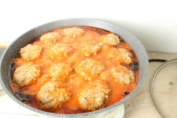 Meatballs in red tomato sauce cooking in a pan close-up