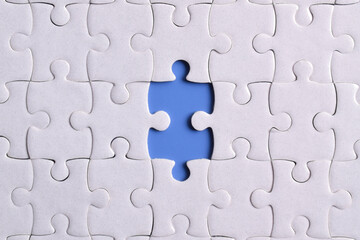 White puzzle with missing piece on blue background, closeup