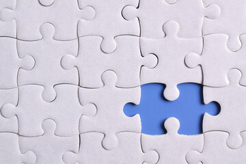 White puzzle with missing piece on blue background, closeup