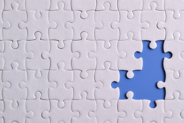 Fototapeta premium White puzzle with missing piece on blue background, closeup