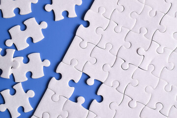 White puzzle pieces on blue background. Flat lay. Top view