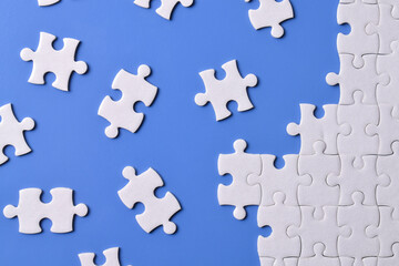 Naklejka premium White puzzle pieces on blue background. Flat lay. Top view