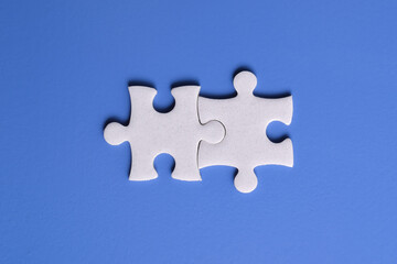 Obraz premium Two white puzzle pieces on a blue background. Top view