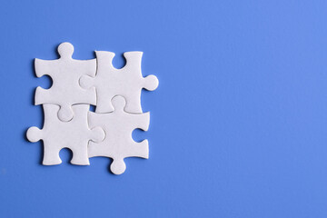 Four puzzle pieces on blue background. The concept of finding the right solutions in teamwork.