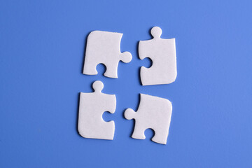 Four puzzle pieces on blue background. The concept of finding the right solutions in teamwork.