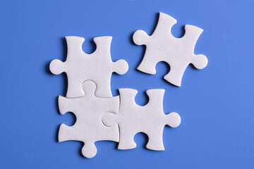 Four puzzle pieces on blue background. The concept of finding the right solutions in teamwork.