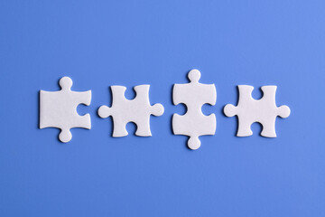 Four puzzle pieces on blue background. The concept of finding the right solutions in teamwork.