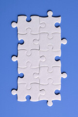 White puzzle pieces on blue background, top view. Space for text