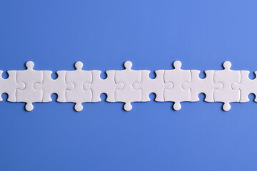 White puzzle pieces forming a line on blue background