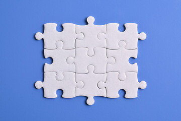 White puzzle pieces on blue background, top view. Space for text