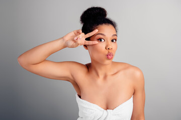 Young cheerful woman with natural skin posing playfully against a grey background, showcasing...