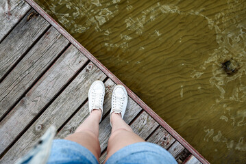 Feet on wooden pier on swimming lake.