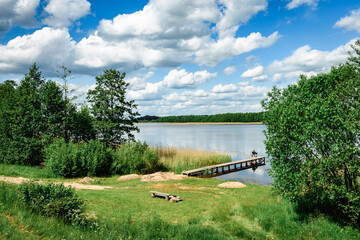 A man is fishing from the shore on a lake with a fishing rod.