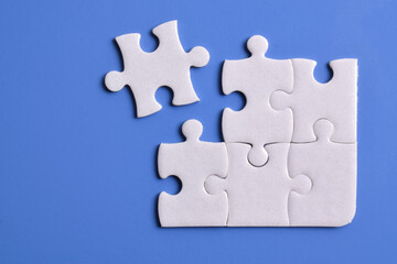 White puzzle pieces on blue background. Flat lay. Top view