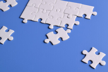 White puzzle pieces on blue background, top view