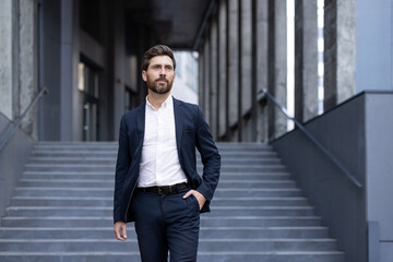 A well-dressed businessman confidently walks down outdoor stairs, exuding professionalism and...