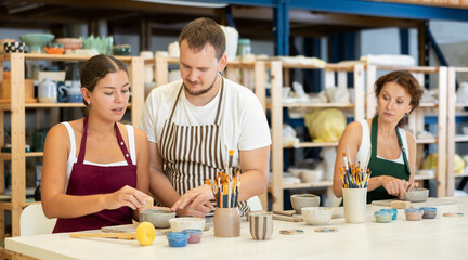 Experienced potter explains to students how to shape clay to make beautiful ceramic dishes
