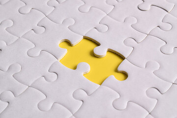 Obraz premium White puzzle with missing piece on yellow background, closeup