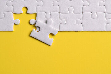 White puzzle pieces on yellow background. Flat lay. Top view