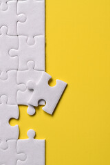 Obraz premium White puzzle pieces on yellow background. Flat lay. Top view