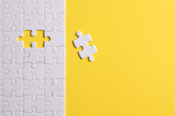 White puzzle pieces on yellow background. Flat lay. Top view