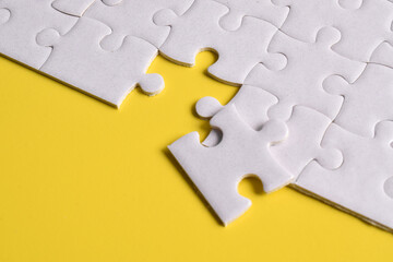 Obraz premium White puzzle pieces on yellow background. Top view