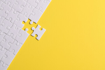 White puzzle pieces on yellow background. Flat lay. Top view