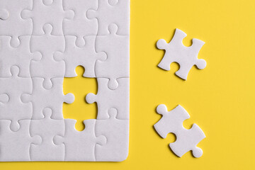 Fototapeta premium White puzzle with missing piece on yellow background. Flat lay. Top view