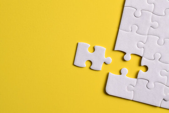 White puzzle pieces on yellow background. Flat lay. Top view