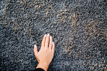 a woman's hand touching the grey Interior pile carpet