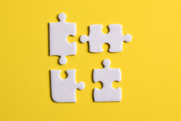 Four puzzle pieces on yellow background. The concept of finding the right solutions in teamwork.