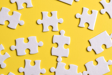 White puzzle pieces on yellow background, top view