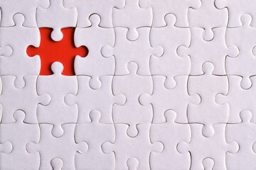 White puzzle with missing piece on red background, closeup