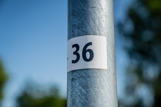 close up of metal utility pole with number 36 label on white sticker outdoor scene identification marking infrastructure blue sky background numeric tag on street pole with shallow depth of field